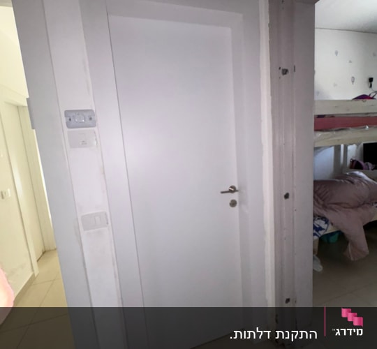 דלת לבנה בחדר פנימי עם ידית כסופה